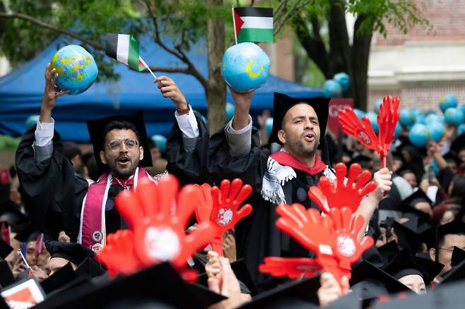 도널드 트럼프 미국 대통령의 압박에도 29일(현지시간) 하버드대 일부 졸업생들이 팔레스타인을 지지해 팔레스타인 깃발과 지구본을 흔들고 있다. 지구본은 팔레스타인과 가자 전쟁이 특정 지역의 문제가 아니라 전세계적인 정의와 자유의 문제로 봐야 한다는 메시지를 보이기 위한 것이다. 2025.05.29. /AFPBBNews=뉴스1