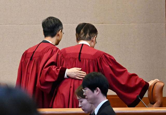 문형배(왼쪽) 당시 헌법재판소장 권한대행이 4월 4일 서울 종로구 헌재 대심판정에서 윤석열 대통령 탄핵심판 인용 결정을 선고한 뒤 김형두 재판관의 등을 두드리며 함께 심판정을 나서고 있다. 사진공동취재단