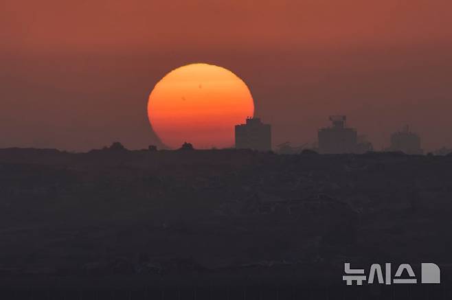 [가자지구=AP/뉴시스] 29일(현지 시간) 가자지구의 파괴된 건물 실루엣 뒤로 해가 지는 모습이 이스라엘 남부에서 관측되고 있다. 2025.05.30.