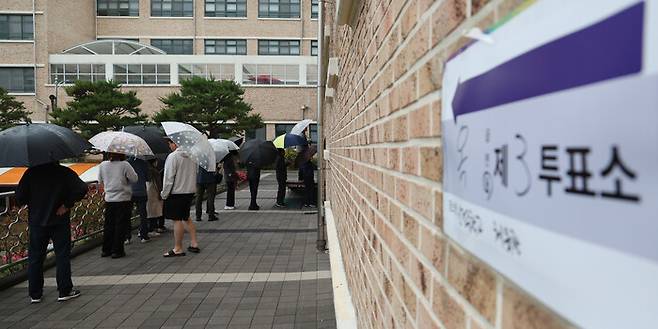 제21대 대통령 선거일인 3일 울산시 남구 신정중학교 체육관에 마련된 옥동 제3투표소에서 유권자들이 우산을 쓰고 투표를 기다리고 있다. 연합뉴스
