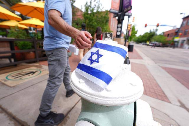 친이스라엘 행사 참가자들을 상대로 한 이집트 출신 불법 체류 망명 신청자의 화염병 투척 공격 이튿날인 지난달 22일 사건이 일어난 미국 콜로라도주 볼더의 볼더카운티 법원 근처 펄스트리트몰 동쪽 끝 차량 진입 방지 말뚝 상단에 부착된 이스라엘 국기를 행인이 만지고 있다. 볼더=AP 연합뉴스