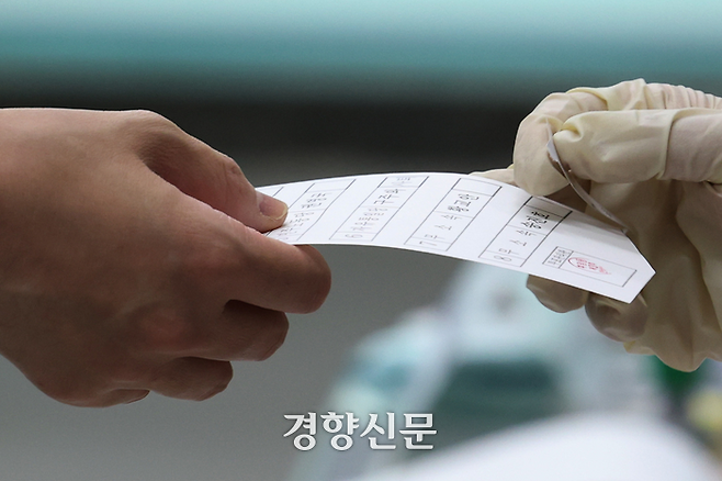 제21대 대통령 선거일인 3일 서울 용산구 삼광초등학교 후암동제3투표소를 찾은 시민이 투표용지를 받아들고 있다. 정효진 기자