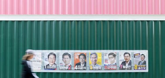 Pedestrians walk past an election banner showing presidential candidates near Sinchon Station in Seodaemun District, central Seoul, on June 2. [NEWS1]