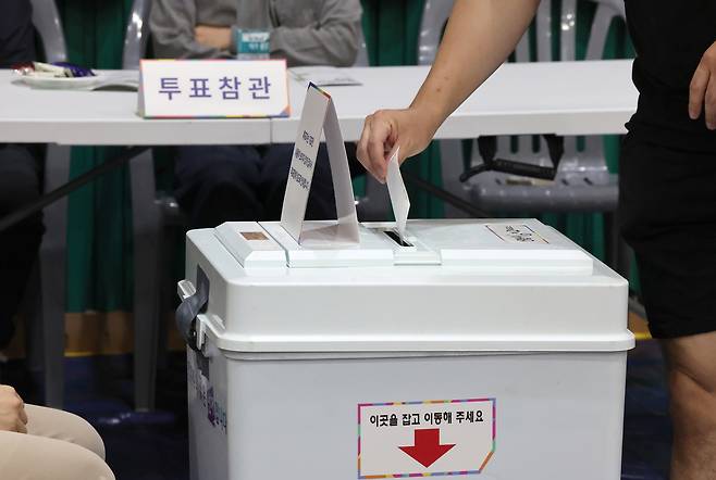 제21대 대통령선거 투표일인 3일 오후 울산 남구 월평초등학교 체육관에 설치된 신정4동 제2투표소에서 투표참관인들이 지켜보는 가운데 한 유권자가 기표를 마친 투표지를 투표함에 넣고 있다. [연합]