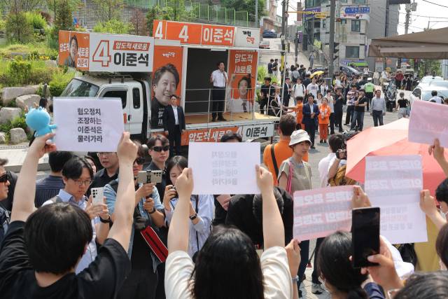 ▲개혁신당 이준석 대선후보가 30일 서울 동작구 중앙대학교에서 유세 중인 가운데 일부 학생들이 최근 이 후보의 TV토론 여성 신체 관련 발언을 규탄하며 팻말을 들고 있다. ⓒ연합뉴스