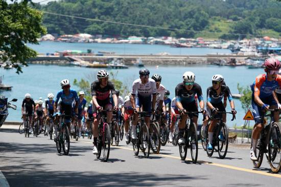 4일 열린 '투르 드 경남' 첫 날 경기에서 선수들이 통영 바다를 배경으로 언덕을 달리고 있다. 사진=경남도