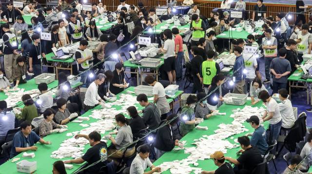 제21대 대통령 선거일인 3일 오전 부산 부산진구청에 마련된 부암1동 제4투표소에서 유권자들이 투표하기 위해 길게 줄을 서 있다(위). 이날 부산 남구 부경대 대연캠퍼스 체육관에 마련된 개표소에서 개표 사무원들이 투표지 분류 작업을 하고 있다. 이재찬·김종진 기자 chan@