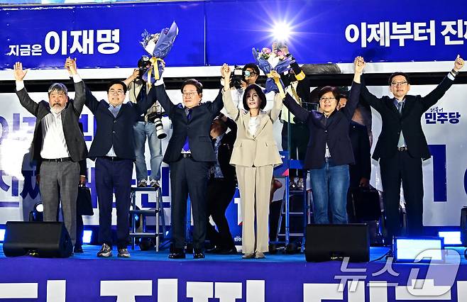 제21대 대통령 선거에서 당선이 확실해진 이재명 더불어민주당 후보가 김혜경 여사와 4일 오전 서울 여의도 국회 앞에 마련된 개표방송 야외 무대에 올라 꽃다발을 들어보이고 있다. (공동취재) 2025.6.4/뉴스1 ⓒ News1 안은나 기자