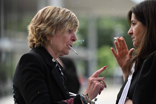 프랑스 미디어 기업가 미셸 미미 마르샹과 텔레비전 진행자 카른 르 마르샹이 지난달 파리 법원 앞에서 담배를 피우고 있다. /연합뉴스