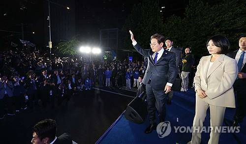 21대 대통령 당선이 확실시되는 더불어민주당 이재명 대선 후보와 부인 김혜경 여사가 4일 새벽 서울 여의도 국회 인근에서 당 주최로 열린 국민개표방송 행사에 참석해 시민들을 향해 손들어 인사하고 있다. 연합뉴스