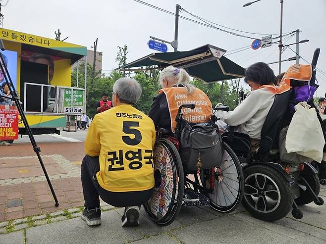 권영국 민주노동당 대통령 후보가 2일 오전 서울 종로구 마로니에공원 앞에서 박경석 전국장애인차별철폐연대 대표 옆에 앉아 다른 활동가의 발언을 듣고 있다. 류석우 기자 raintin@hani.co.kr