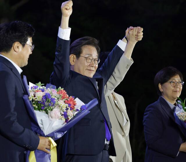 이재명 더불어민주당 후보가 제21대 대통령 당선이 확실시된2025년 6월4일 오전 1시20분께 서울 여의도 국회 인근에서 당 주최로 열린 국민개표방송 행사에 참석해 김혜경 여사와 함께 시민들을 향해 두 팔을 들어 인사하고 있다. 공동취재사진