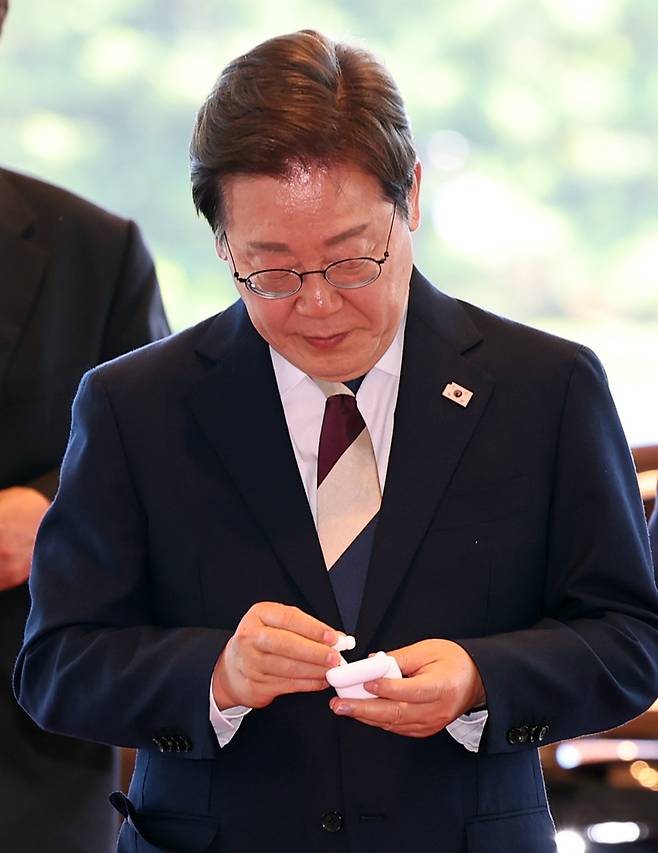 이재명 대통령이 4일 서울 용산 대통령실 청사로 들어서며 이어폰을 정리하고 있다. 연합뉴스