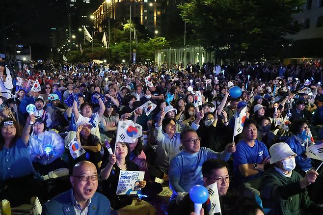 4일 서울 여의도 국회 인근에서 더불어민주당 주최로 열린 제21대 대통령 선거 국민개표방송 행사에 참석한 시민들이 방송예측시스템에서 이재명 대선 후보의 ‘당선 확실’이 나오자 환호하고 있다. [사진 출처 = 연합뉴스]