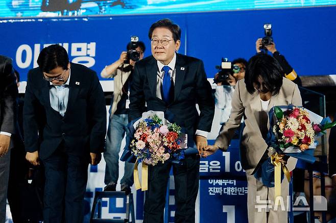 [서울=뉴시스] 조성우 기자 = 이재명 대통령과 김혜경 여사가 4일 오전 서울 여의도 국회 앞에서 열린 국민 개표방송 행사에서 꽃다발을 받은 뒤 시민들을 향해 인사하고 있다. (공동취재) 2025.06.04. photo@newsis.com