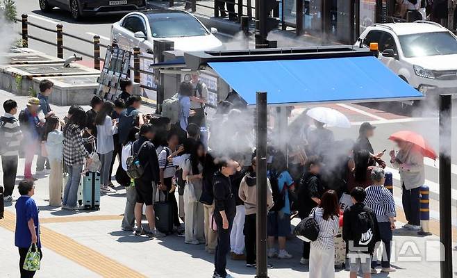 [부산=뉴시스] 하경민 기자 = 무더운 날씨를 보인 4일 부산 동구 부산역 광장 횡단보도 앞에 설치된 그늘막 아래서 시민과 관광객들이 쿨링포그를 맞으며 더위를 식히고 있다. 2025.06.04. yulnetphoto@newsis.com