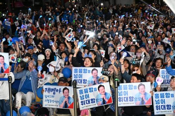 3일 밤 이재명 더불어민주당 대선 후보의 대통령 당선이 확정되자 서울 여의도 국회 앞에 모여 있던 지지자들이 태극기와 응원봉을 흔들며 환호하고 있다. 홍윤기 기자