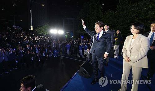 인사하는 이재명 후보와 김혜경 여사     (서울=연합뉴스) 김주성 기자 = 제21대 대통령 당선이 확실시되는 더불어민주당 이재명 대선 후보와 부인 김혜경 여사가 4일 서울 여의도 국회 인근에서 당 주최로 열린 국민개표방송 행사에 참석해 시민들을 향해 손들어 인사하고 있다. 2025.6.4 [공동취재]