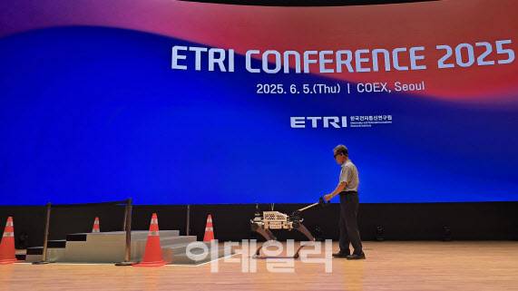 한국전자통신연구원이 5일 서울 강남구 코엑스에서 개최한 ‘ETRI 콘퍼런스 2025’에서 방승찬 ETRI 원장이 시각장애인을 위한 인공지능(AI) 안내 로봇 ‘에디(EDDI)’와 함께 보행하며 계단 오르내리기를 시연하고 있다.(사진=ETRI)