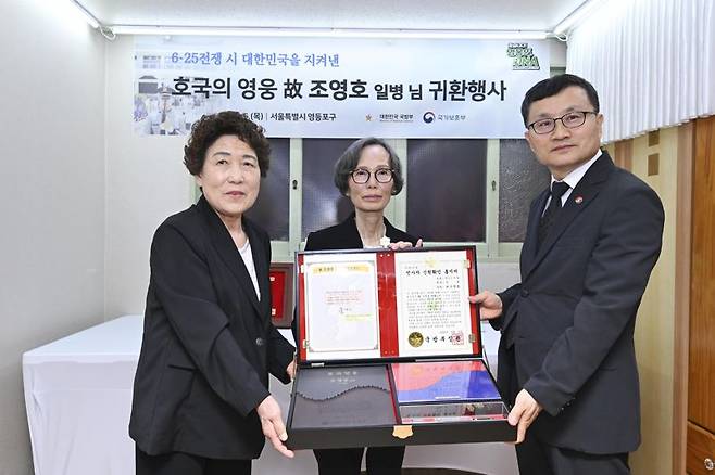 이근원 국방부유해발굴감식단장과 고 조영호 일병의 유가족(왼쪽부터 작은 딸 조한금 씨, 큰딸 조한춘 씨)이 '호국의 얼' 함을 들고 기념사진을 촬영하고 있다. 국방부 제공