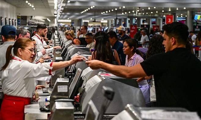 지난달 24일 미국 플로리다주 마이애미 국제공항에서 승객들이 항공사 직원들에게 필요 서류를 넘겨주고 있다. 사진 AFP 연합뉴스