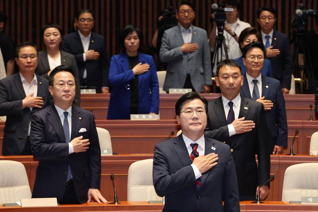 박찬대 더불어민주당 대표 권한대행 겸 원내대표와 박성준 원내수석부대표를 비롯한 의원들이 5일 서울 여의도 국회에서 열린 의원총회에서 국기에 경례하고 있다.  연합뉴스