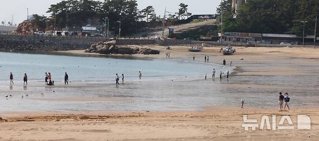 [인천=뉴시스] 전진환 기자 = 초여름 날씨를 보인 22일 오후 인천 중구 을왕리해수욕장을 찾은 관광객들이 바다에 발을 담그고 있다. 인천 중구지역 해수욕장이 다음달 21일 일제히 개장한다. 2025.05.22.  amin2@newsis.com