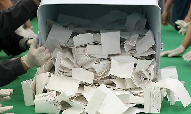 지난 3일 부산 남구 국립부경대학교 대연캠퍼스 체육관에 마련된 개표소에서 개표사무원들이 투표함에서 투표용지를 꺼내고 있다. 뉴스1