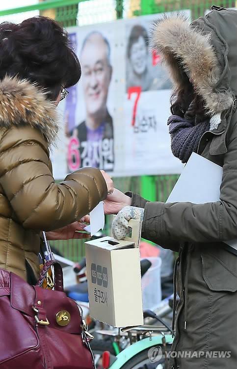 <2012대선> '지금은 출구조사 중'  (서울=연합뉴스) 한종찬 기자 = 18대 대통령선거일인 19일 서울 잠실본동 주민센터에 마련된 투표소 앞에서 출구 조사원들이 투표를 마치고 나오는 시민에게 출구조사를 하고 있다. 2012.12.19 saba@yna.co.kr