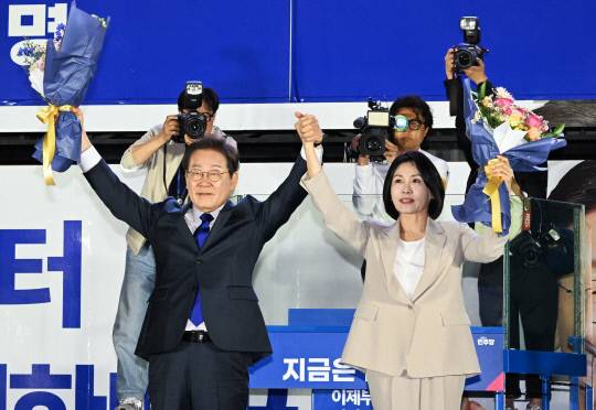 이재명 대통령과 김혜경 여사가 지난 4일 서울 여의도 국회 인근에서 당 주최로 열린 국민개표방송 행사에 참석해 꽃다발을 받고서 시민들을 향해 두 팔을 들어 인사하고 있다. 연합뉴스