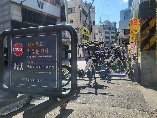 '레드로드 차 없는 거리'라고 쓰여진 표지판 뒤에 전동킥보드, 전기자전거 등 공유형 PM이 주차돼 있다.ⓒ데일리안 허찬영 기자