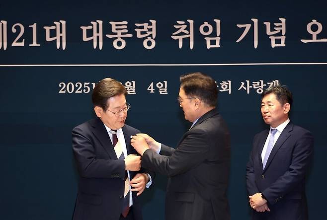 우원식 국회의장이 2025년 6월4일 국회 사랑재에서 열린 제21대 이재명 대통령 취임 기념 오찬에서 이 대통령에게 ‘진관사 태극기’ 배지를 달아주고 있다. 우원식 국회의장 페이스북 갈무리