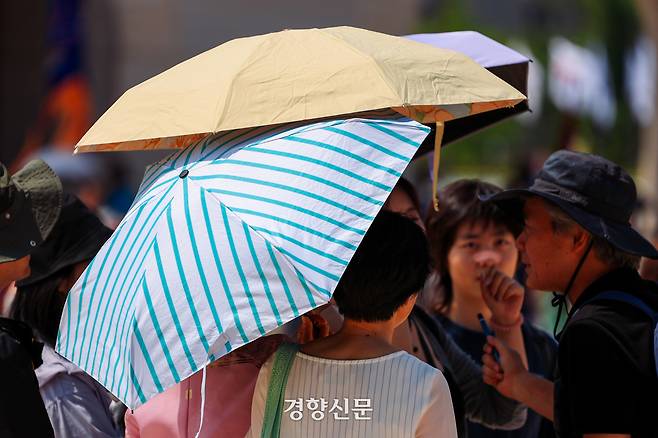 6일 서울 경복궁을 찾은 관광객들이 양산을 펼쳐 햇빛을 가리고 있다。 이준헌 기자