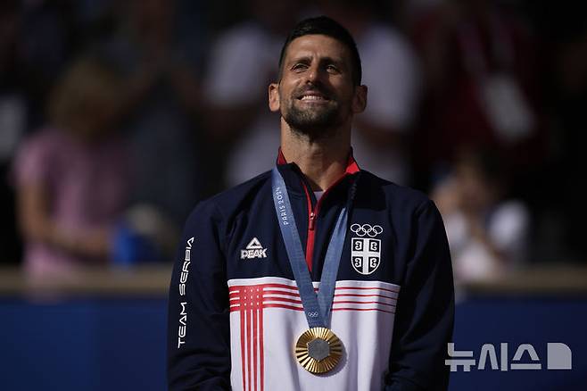 [파리=AP/뉴시스] 노바크 조코비치(2위·세르비아)가 지난해 8월4일(현지시각) 프랑스 파리의 스타드 롤랑가로스에서 열린 2024 파리올림픽 테니스 남자 단식 정상에 올라 금메달을 걸고 시상대에 올라 포즈를 취하고 있다. 조코비치는 결승전에서 카를로스 알카라스(3위·스페인)를 2-0(7-6<7-3> 7-6<7-2>)으로 꺾고 금메달을 따며 마침내 '골든 그랜드슬램'을 완성했다. 2024.08.05.