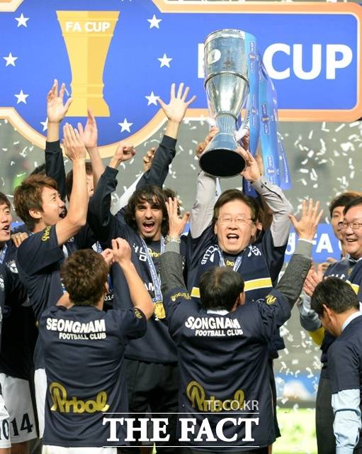 이재명 대통령이 성남 시장으로 성남FC 구단주로 재직하던 2014년 11월 하나은행 FA컵에서 우승한 뒤 선수단과 함께 우승 트로피를 들며 환호하고 있다./뉴시스