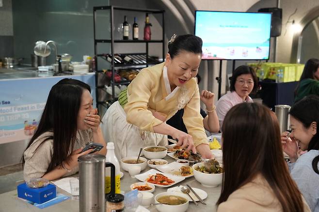 지난달 24일 부산에서 외국인과 국내 관광객을 상대로 열린 무료 행사에서 ‘이모카세’ 김미령씨(왼쪽에서 두번째)가 각종 나물로 비빔밥을 만들어 주고 있다. 한국관광공사 제공