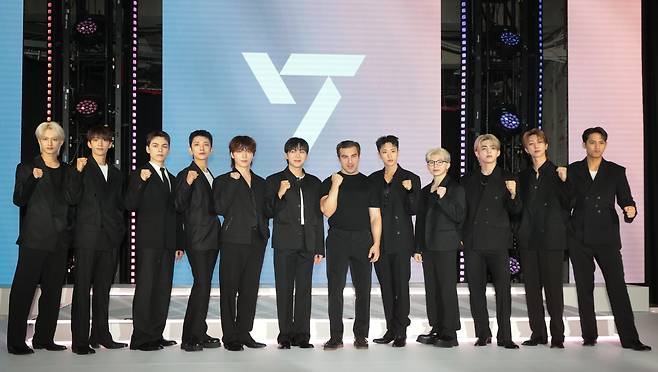 Airbnb co-founder and CEO Brian Chesky (seventh from left) and K-pop group Seventeen pose for photos during a press conference on Wednesday in Yongsan, Seoul. (Yonhap)