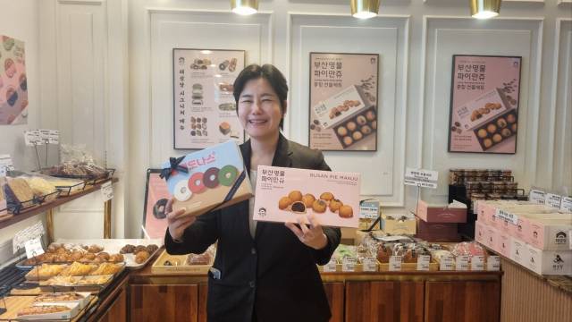 태성당 이나겸 대표가 부산의 느낌이 듬뿍 담긴 제품을 들고 환하게 웃고 있다.