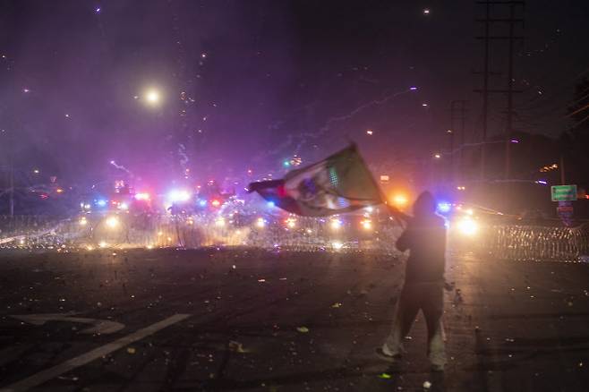 7일(현지시간) 캘리포니아주 로스앤젤레스에서 강압적인 불법 이민자 단속에 반발하는 시위대가 연방 경찰과 대치하는 가운데 한 시위자가 멕시코 국기를 흔들고 있다.(사진=AFP)