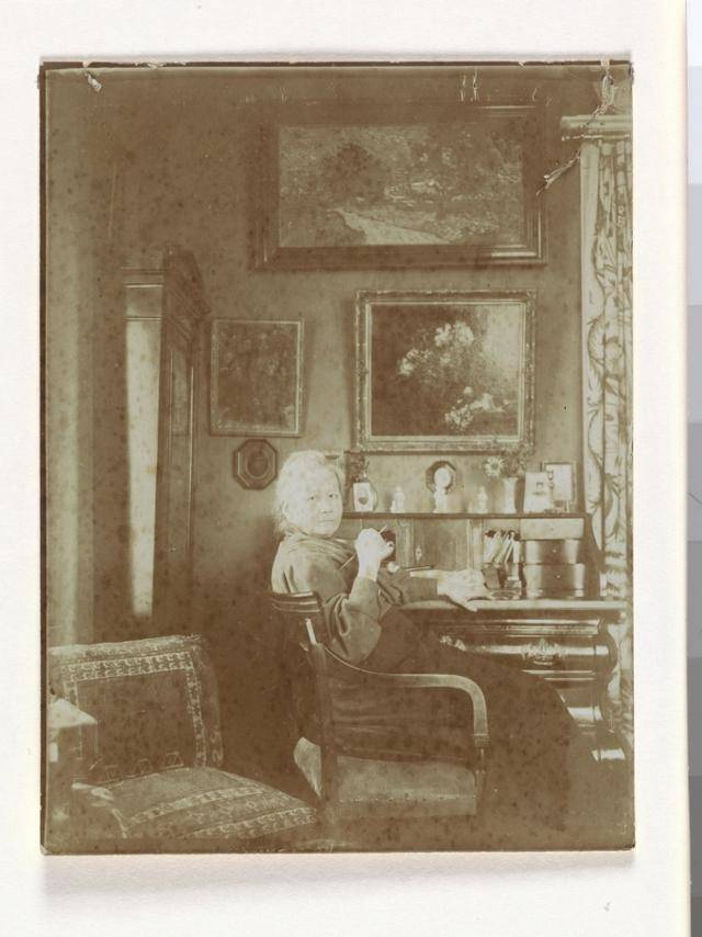 네덜란드 암스테르담의 자택 거실 책상 앞에 앉아 있는 요 반 고흐 봉어르의 모습. 1909년으로 추정된다. 책상 뒤편 벽에 빈센트 반 고흐의 그림 '은선초 꽃병'과 '황혼 풍경'이 보인다. 아트북스 제공