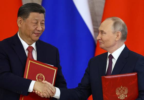 지난달 8일(현지시간) 블라디미르 푸틴 러시아 대통령(오른쪽)과 시진핑 중국 국가주석이 러시아 모스크바 크렘린궁에서 정상회담 후 '신시대 전면적 전략적 협력 동반자 관계 강화 성명' 서명식에서 악수하고 있다. 로이터=연합뉴스