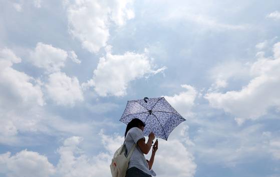 A citizen blocks the sun using a parasol in Gwanghwamun, central Seoul, on June 8. [NEWS1]