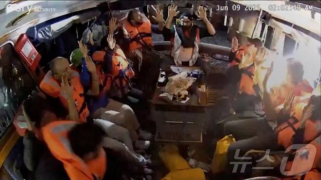 기후활동가 그레타 툰베리를 포함해 12명이 탑승한 자유선단연합의 매들린호에 탑승한 이들이 9일(현지시간) 누군가 선박에 들어오자 손을 들고 있는 모습. 매들린호는 영유아 분유, 밀가루, 쌀, 기저귀, 여성 생리대, 의료용품 등을 싣고 지난 1일 이탈리아 시칠리아를 출발해 가자지구로 향했다. 25.06.09 ⓒ 로이터=뉴스1 ⓒ News1 김예슬 기자