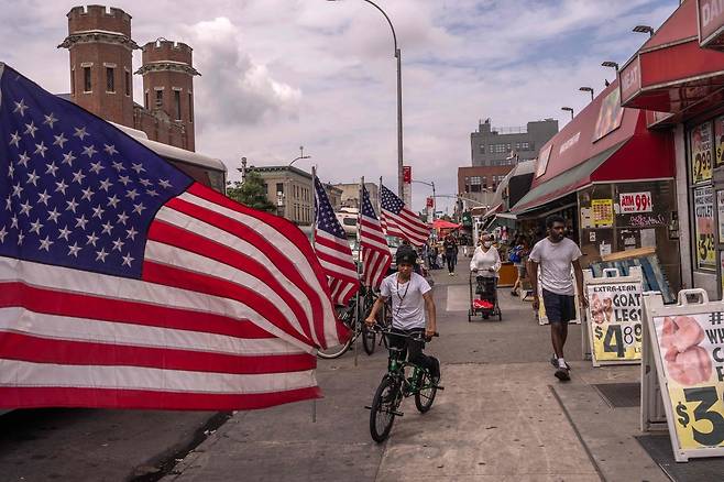 8일(현지시간) 미국 뉴욕 브루클린 자치구의 리틀 아이티 지역에서 사람들이 미국 성조기들이 나란히 세워진 도로를 걷고 있다. [AFP]