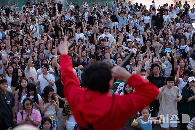 [서울=뉴시스] 황준선 기자 = 8일 오후 서울 서초구 반포한강공원 수변무대에서 열린 한강 무소음 DJ 파티를 찾은 시민들이 무선 헤드폰을 착용하고 춤을 추고 있다. 2025.06.08. hwang@newsis.com