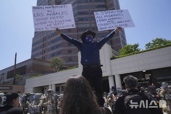 [로스앤젤레스=AP/뉴시스] 8일(현지 시간) 미 캘리포니아주 로스앤젤레스 도심의 메트로폴리탄 구치소 인근에서 이민세관단속국(ICE)의 불법 이민자 단속 및 체포에 항의하는 시위대가 손팻말을 들고 구호를 외치고 있다. 도널드 트럼프 대통령은 불법 이민자 단속에 항의하는 시위에 참여하는 사람들은 마스크를 착용해서는 안 된다고 밝혔다. 2025.06.09.