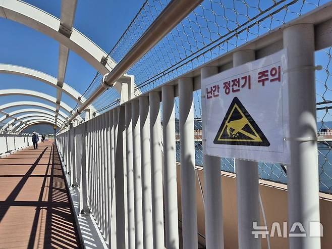 [부산=뉴시스] 김민지 기자 = 5일 오전 부산 도시철도 3호선 구포역과 화명생태공원을 연결하는 보행교 '감동나룻길 리버워크'에 난간 정전기 발생을 주의하는 안내문이 걸려 있다. 2025.06.09. mingya@newsis.com