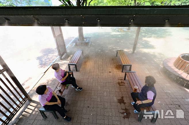 [서울=뉴시스] 황준선 기자 = 한낮 기온이 30도를 넘는 무더운 날씨를 보인 9일 오후 서울 여의도공원에서 시민들이 쿨링포그를 맞으며 휴식을 취하고 있다. 2025.06.09. hwang@newsis.com