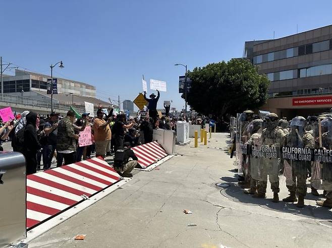 미 LA에서 불법이민 단속에 항의하는 시위대와 이를 막아선 주방위군 (로스앤젤레스=연합뉴스) 임미나 특파원 = 8일(현지시간) 미국 로스앤젤레스(LA) 도심의 연방 구금시설인 '메트로폴리탄 디텐션 센터'(Metropolitan Detention Center, 이하 MDC) 앞에서 주방위군이 시위대와 대치하고 있다. 시위대는 미 이민세관단속국(ICE)의 대대적인 불법이민자 단속에 반발하는 시위를 사흘째 벌이고 있다. mina@yna.co.kr