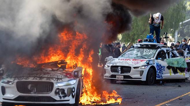 지난 8일 미국 캘리포니아주 로스앤젤레스에서 한 시위자가 차량에 불을 지르고 있다./로이터 연합뉴스